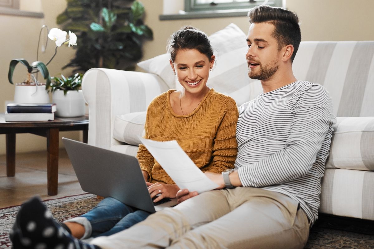 A couple sitting on the floor and reading a document together