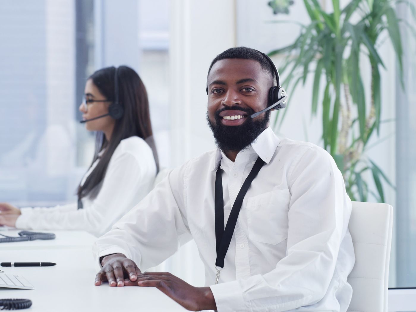 A smiling contact-centre adviser wearing a headset at his workstation
