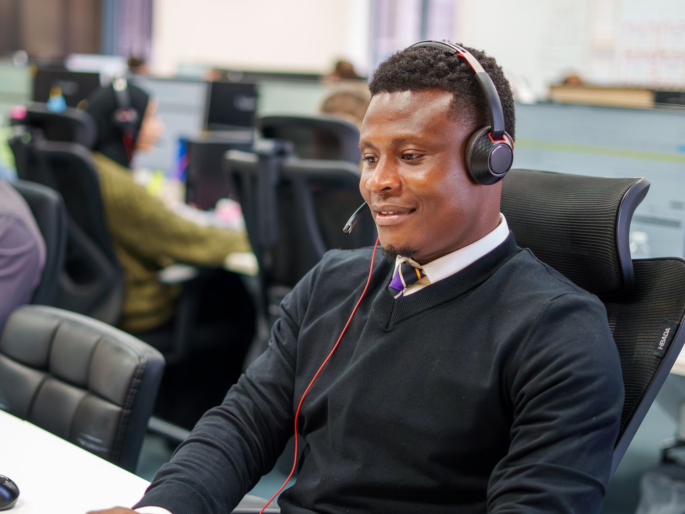 A support adviser wearing a headset and working at his desk