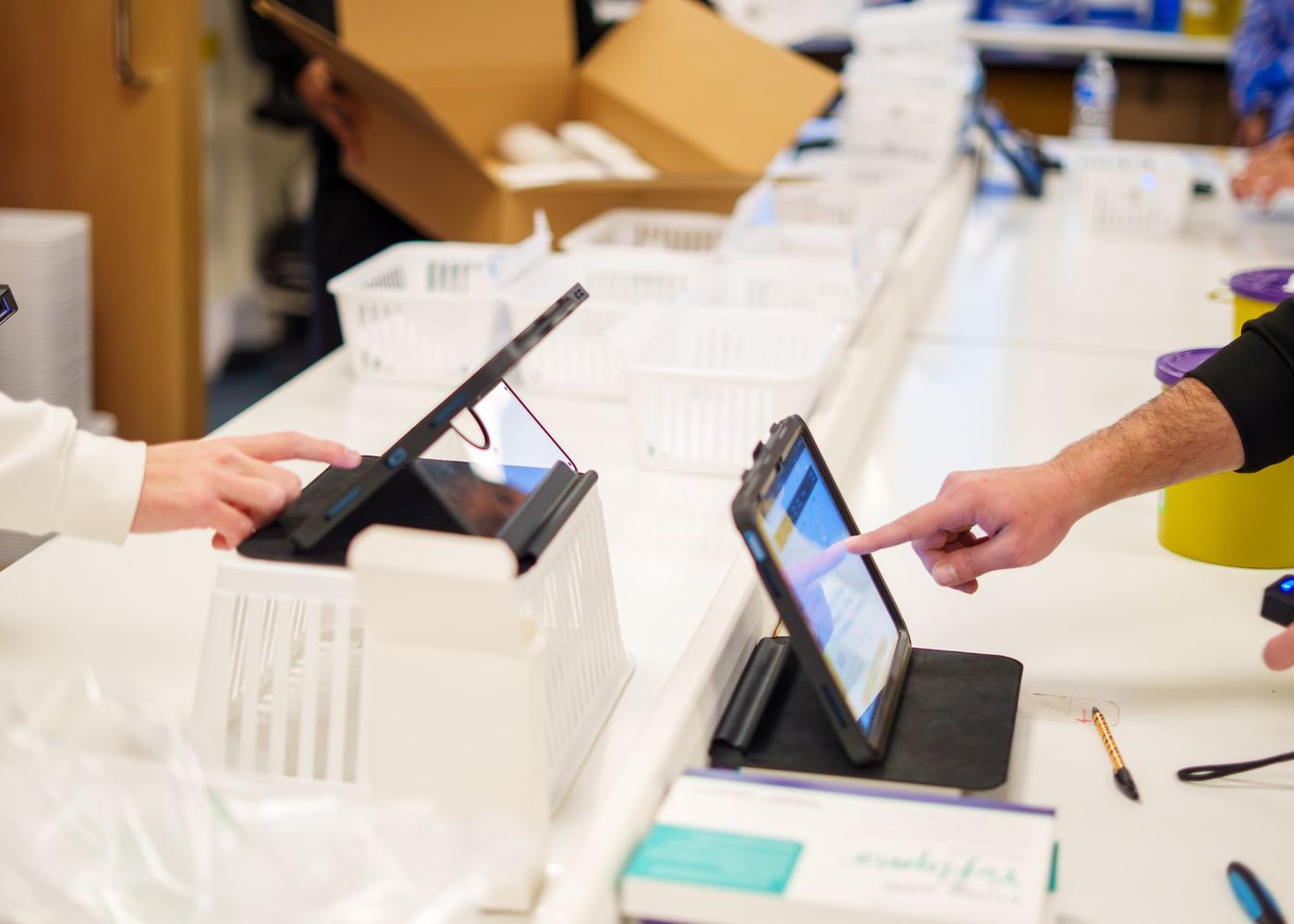 Two team members using tablets to scan and sign for parcels at the pharmacy dispatch counter