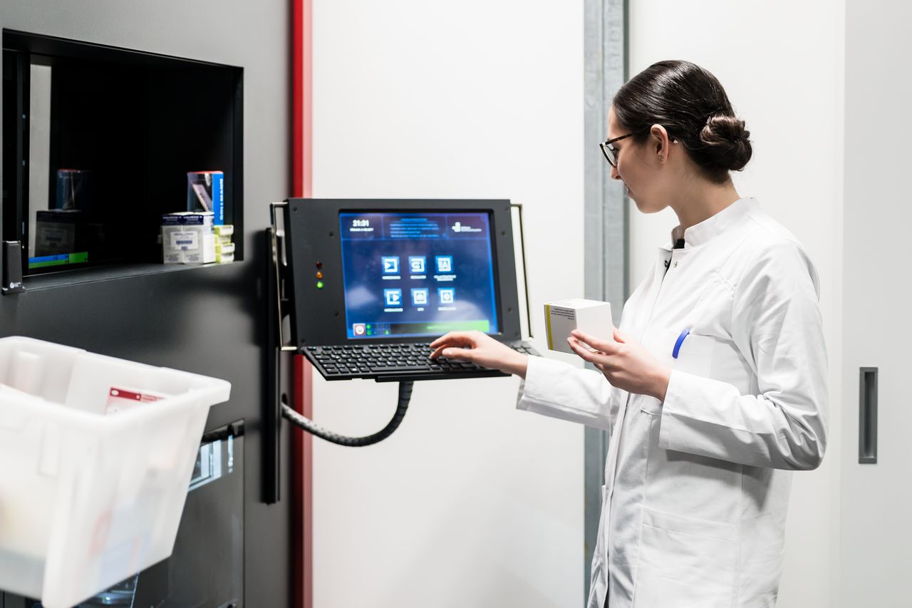 A pharmacist using the touchscreen of an automated dispensing system